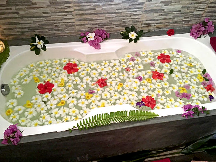 Blumenbad - Badewanne gefüllt mit Wasser und Blüten